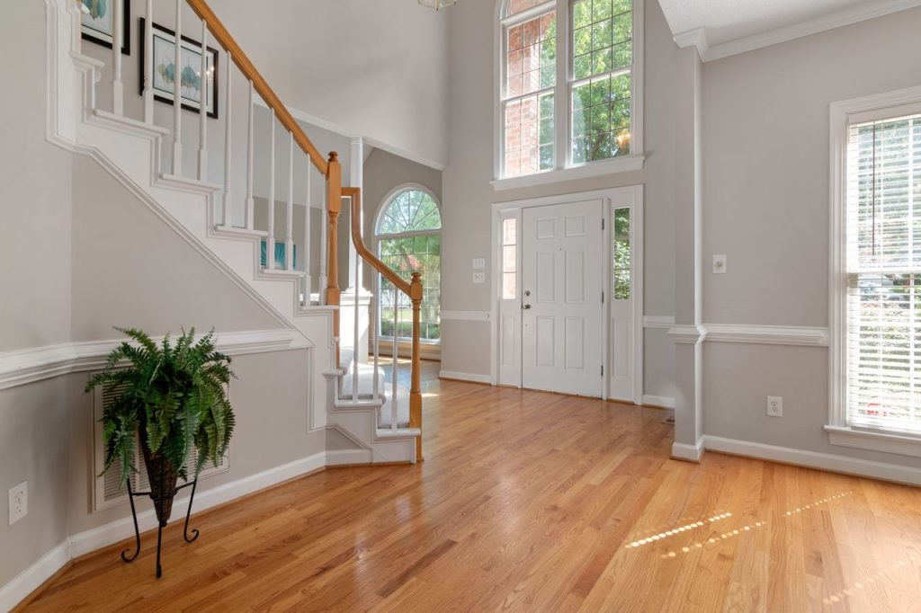 Elegant entrance with a wooden staircase and large windows, perfect for modern interiors.